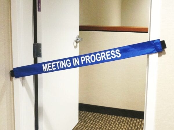 A “Meeting in Progress” Banner on a Conference Room’s Doorway